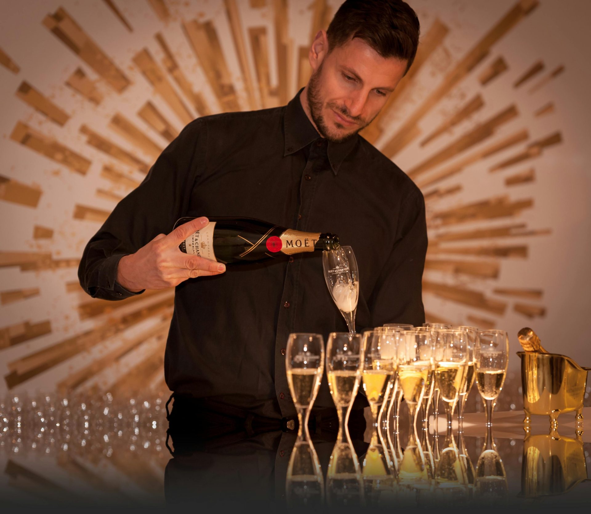 Bartender elegantly pouring champagne into glasses at a sophisticated indoor event.